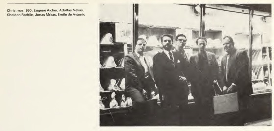 Men wearing suits posing in front of a storefront window