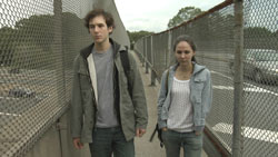 A teenage couple walk across a bridge