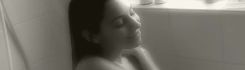 Film still of a woman sitting in the shower