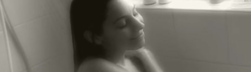 Film still of a woman sitting in the shower