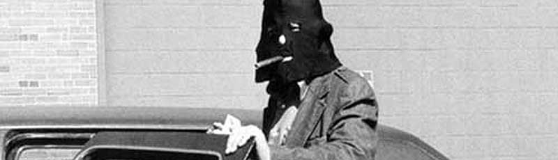 Man in a black hood getting into a car