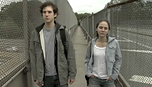 Teenage boy and girl walk across a bridge