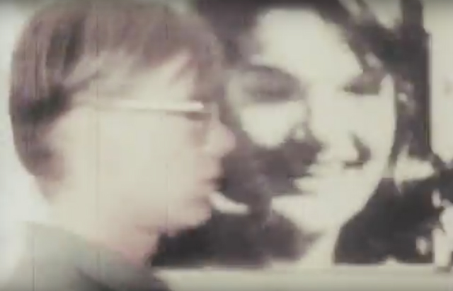 Andy Warhol Andy Warhol walking in front of one of his portraits of Jackie Kennedy