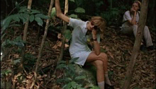 Blonde woman in a blue dress sitting in the jungle
