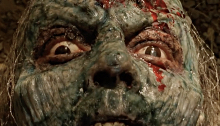 Green faced zombie covered in blood