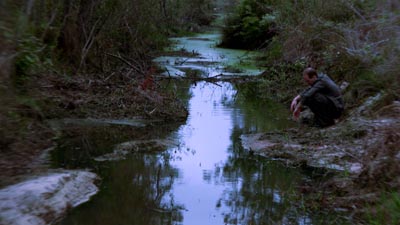 A man washes his hands in a stream