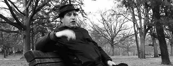 A white male blowhard pontificates while sitting on a park bench