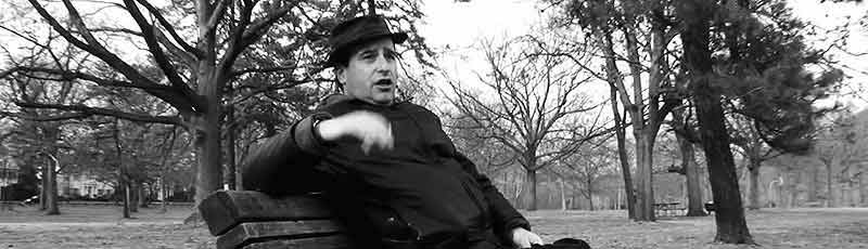 A white male blowhard pontificates while sitting on a park bench
