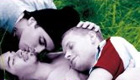 Three young people cuddle in the grass
