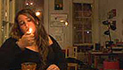 Woman sitting at a table lighting a cigarette