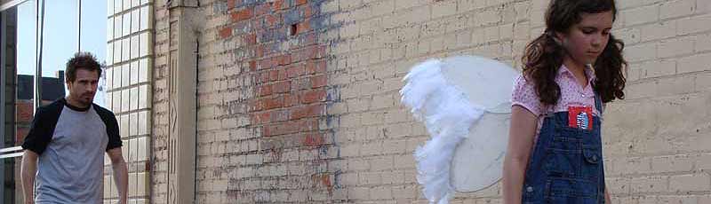 Man walks menacingly towards a young girl wearing angel wings