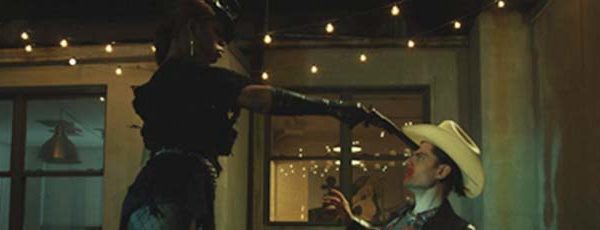 Laverne Cox points a gun at the head of a man wearing a cowboy hat