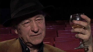Jonas Mekas drinking a glass of wine while being interviewed
