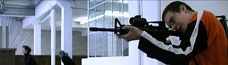 Man wearing glasses pointing a gun
