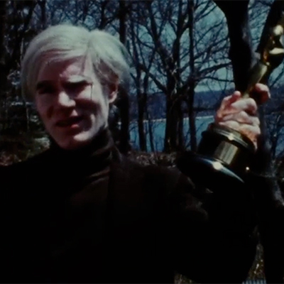 Andy Warhol holds up an Oscar statuette