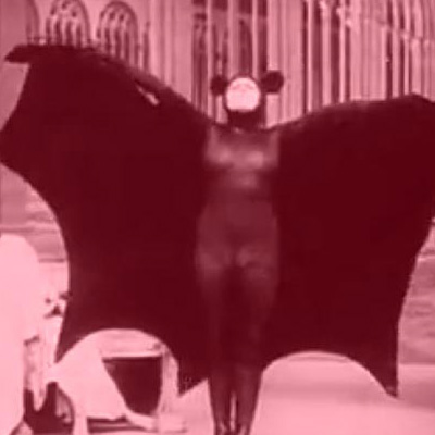 A woman in a bad costume spreads her wings in a scene from Louis Feuillade's film Vampires.