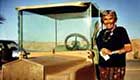Senior citizen standing next to her golf cart in the desert