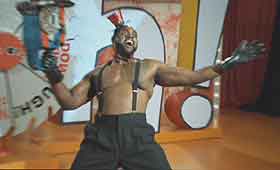 The Uh-Oh Show Black man wearing suspenders with no shirt on a game show set