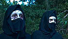 Two disfigured people wearing hoods and masks
